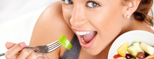 Slim young woman eating fruit salad