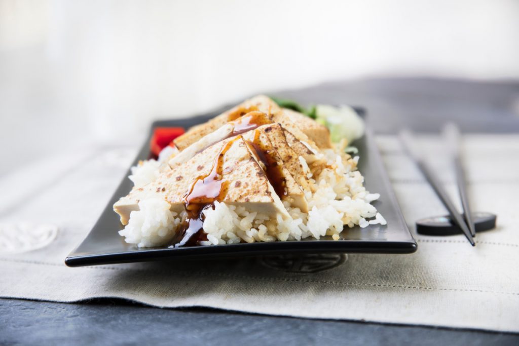 Aujourd’hui, nous vous proposons un focus sur le soja car les aliments à base de soja fournissent des protéines de haute qualité souvent négligées dans notre alimentation. En fin d’article, vous trouverez une excellente recette Herbalife Nutrition de tofu grillé ! Qu’est-ce que le soja ? Le soja n’est pas un aliment de base dans le monde occidental. Néanmoins, les aliments traditionnels à base de soja, comme le tofu, le miso (retrouvez nos recettes de miso) et le tempeh, constituent la base de l’alimentation en Asie de l’Est depuis des siècles, où ils sont appréciés non seulement pour leur polyvalence mais aussi pour la saine alimentation qu’ils offrent. Le soja déborde d’éléments nutritifs Bien que tous les haricots fournissent des protéines, en matière de qualité des protéines, c’est le soja qui arrive en tête de liste. Les protéines sont composées de petits éléments constitutifs appelés acides aminés. Certains acides aminés sont qualifiés d’essentiels, ce qui signifie que ce sont les aliments qui nous les fournissent car notre organisme, lui, n’est pas en mesure de les fabriquer. Une protéine qui contient tous les acides aminés essentiels est dite « complète » – et le soja représente l’une des rares protéines complètes présentes dans le monde végétal. Le soja est faible en gras saturés et, comme tous les aliments d’origine végétale, il est naturellement dépourvu de cholestérol. Le soja procure également du calcium, du magnésium, du phosphore, du potassium et des vitamines B, ainsi que des acides gras oméga-3. Si vous essayez d’intégrer davantage de protéines végétales à votre alimentation, vous voudrez peut-être essayer le soja. Avec un grand choix de produits à base de soja disponibles, c’est plus facile que jamais ! Voici quelques-unes des formes de soja les plus populaires. Formes de soja Les edamames sont des fèves de soja vertes fraîches. La plupart du temps, vous pouvez les trouver surgelés, soit en gousse, soit déjà écossés. Après une brève cuisson dans de l’eau salée, ils peuvent être consommés en collation ou ajoutés aux soupes et salades. Le tempeh est fabriqué à partir de fèves de soja partiellement cuites, qui fermentent et qui sont ensuite transformées en un bloc ferme. Le tempeh étant fermenté, il constitue une source de « bonnes bactéries », ou probiotiques. Le tempeh a une saveur de viande et une texture ferme qui conserve sa forme, il est donc idéal pour les salades et les plats sautés. Le miso est une pâte à base de soja fermenté, ce qui signifie qu’il contient également des probiotiques. Il est utilisé comme base pour les soupes et comme ingrédient dans les sauces, les vinaigrettes et les marinades. Il en existe différentes variétés, et sa couleur peut varier du jaune clair au brun très foncé. En général, le miso clair est moins salé et plus doux en termes de saveur que le miso foncé. La boisson végétale de soja est fabriquée à partir de fèves de soja séchées trempées dans l’eau jusqu’à ce qu’elles soient réhydratées, puis broyées avec de l’eau. Le « lait » ainsi obtenu est vendu comme boisson ou transformé en yaourt. La boisson de soja et le yaourt de soja contiennent chacun environ 7 grammes de protéines par portion de 250 ml. Vous pouvez utiliser le lait de soja comme boisson à part entière ou vous pouvez le remplacer par du lait ordinaire dans la plupart des recettes ou dans les boissons protéinées. Les noix de soja sont des fèves de soja entières grillées. À elles seules, elles constituent une bonne collation, et elles sont aussi bonnes en salades, en mélanges de fruits séchés et en céréales. Les noix de soja (et le beurre de noix de soja, fabriqué à partir de noix de soja moulues) contiennent un peu plus de protéines et un peu moins de gras que les arachides ou le beurre d’arachide. Les poudres de protéines de soja et les substituts de viande sont fabriqués à partir de farine de soja dont la graisse a été, en majeure partie, retirée. Les poudres peuvent être ajoutées aux milk-shakes ou mélangées à de la farine d’avoine, et les substituts de viande de soja peuvent être utilisés dans toutes sortes de recettes en remplacement de la viande ou de la volaille. Le tofu est un fromage fabriqué essentiellement à partir de « lait » de soja. Sa texture varie d’extra-ferme à extra-douce et sa saveur est très douce. Il se mélange bien avec presque tout, des sauces épicées aux fruits naturellement sucrés. Le tofu plus ferme peut être grillé ou sauté, tandis que le tofu plus doux et plus crémeux peut être utilisé dans les milk-shakes ou être sucré et garni de fruits en dessert. Votre guide rapide du tofu Il existe tellement de types de tofu différents qu’il peut être difficile de s’y retrouver. Je crains que beaucoup d’occidentaux ne rejettent le tofu alors qu’il peut vraiment être goûteux et qu’il présente énormément d’avantages. Cela peut valoir la peine de trouver quelques types de tofu préférés. Le tofu soyeux Parmi tous les types de tofu, le tofu soyeux est celui qui contient le plus d’humidité. Il possède une texture douce, très lisse, semblable à celle de la crème pâtissière et a tendance à s’effriter facilement. Il existe également différents degrés de fermeté. Par conséquent, ne partez pas du principe que tous les tofus soyeux sont mous. Le tofu soyeux est le meilleur tofu à fouetter au mixeur ou au robot culinaire. Une fois mixé, le tofu soyeux ajoute une texture onctueuse et un bon apport en protéines aux milk-shakes, soupes et sauces. Le tofu soyeux peut également se transformer en dessert sain une fois mélangé avec des fruits, une touche de miel et un soupçon de cannelle. Vous pouvez aussi le mélanger avec de l’ail et des fines herbes et l’utiliser comme trempette savoureuse pour les légumes crus. Le tofu moyen Le tofu mou ou moyen conserve un peu mieux sa forme que le tofu soyeux, et il est souvent écrasé à la fourchette pour lui conférer une texture molle et friable qui en fait un bon substitut de viande dans les aliments comme la sauce pour pâtes. On l’utilise aussi souvent pour faire une salade d’œufs « sans œufs » en l’écrasant avec un peu de moutarde et de mayonnaise allégée ou avec de l’avocat. Le tofu ferme Parmi tous les tofus, c’est le tofu ferme ou extra-ferme qui possède la texture la plus moelleuse, ce qui signifie qu’il peut être sauté, rôti ou grillé. Pour le rendre encore plus tendre et plus « viandeux », certaines personnes le découpent en tranches et le congèlent (ce qui modifiera sa couleur, mais n’affectera pas son goût) avant de l’utiliser dans leurs recettes. La meilleure recette de tofu grillé Toujours pas attiré par le soja et le tofu ? Essayez cette recette Herbalife Nutrition de tofu rôti. C'est délicieux à la sortie du four ou avec des légumes sautés, et c’est bon froid également. Pensez par exemple à disposer vos tiges de tofu rôties sur une salade pour le déjeuner, ou en prendre quelques morceaux avec quelques tranches de concombre pour une collation rapide. Ingrédients – 1 paquet de tofu ferme (environ 425 g) Pour la marinade – 3 cuillères à soupe de sauce soja légère – 3 cuillères à soupe de vinaigre de riz – 1 cuillère à café de sucre ou de miel – 1 cuillère à café d’huile de sésame – Pincée de gingembre moulu – Pincée de poudre d’ail – Pincée de poivre blanc – Huile d’olive (pour graisser légèrement la plaque de cuisson) Méthode – Fouetter ensemble les ingrédients de la marinade dans un plat peu profond et mettre de côté. – Retirer le tofu de son emballage et égoutter toute l’eau. – Envelopper le bloc de tofu dans des serviettes en papier ou dans un torchon propre et presser doucement pour éliminer toute l’eau qui pourrait rester. – Couper le tofu en triangles, ou en « tiges », et le disposer en une seule couche dans la casserole avec la marinade, en retournant les morceaux pour enrober tous les côtés. – Couvrir d’un film plastique et laisser mariner au réfrigérateur pendant au moins 30 minutes (et jusqu’à 48 heures). Une fois le tofu prêt à cuire : – Préchauffer le four à 180°C. – Enduire une grande plaque de cuisson d’un peu d'huile d’olive pour empêcher le tofu de coller. Vous pouvez recouvrir votre plaque de papier sulfurisé ou de spray de cuisson antiadhésif. – Disposer les morceaux de tofu en une seule couche sur la plaque de cuisson et verser le reste de la marinade sur les morceaux de tofu. – Faire rôtir au four pendant environ 45 minutes, en tournant de temps en temps (et doucement). – Les morceaux doivent être fermes et avoir un beau glaçage marron. – Si ces délicieuses tiges de tofu ne sont pas destinées à être consommées immédiatement, vous pouvez les conserver au réfrigérateur. Ce tofu rôti est délicieux aussi bien chaud que froid. Et vous, comment consommez-vous du soja ?